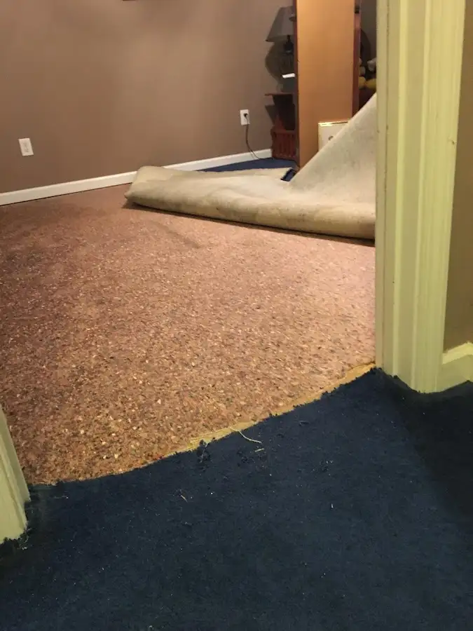 Carpet pad removal revealing water damage during Water Mitigation Services in Valley Falls